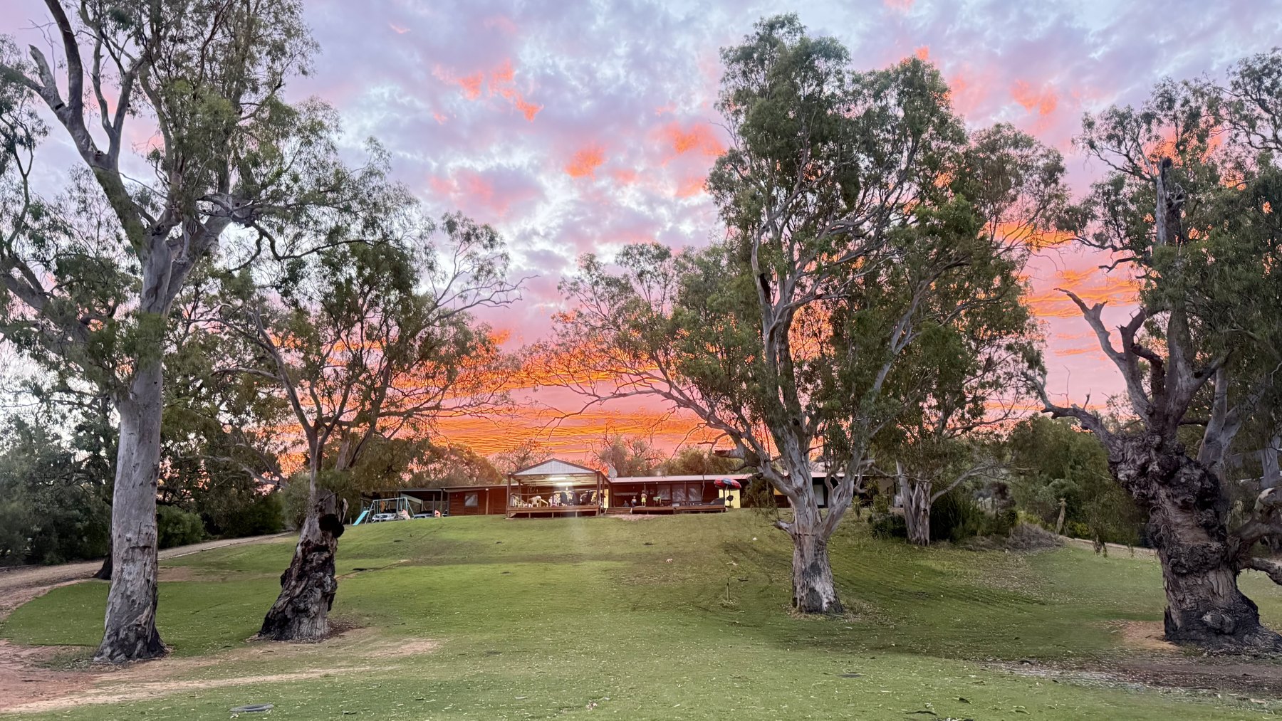 Pink sunset above The Getaway, its lawn and river gums